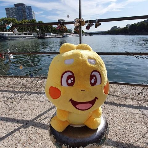 A QooBee plushy sightseeing by a river
